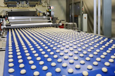Close up of automated biscuit cookies shape forming machine. Selective focus. machine for making cookies in the factory. Conveyor belt with Cookie dough