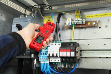 Elektrik mühendisi, elektrik kabinesi kontrolündeki voltaj ve elektrik akımını ölçen bir testçi ve röle koruma sistemindeki kabloları kontrol ediyor. Körfez kontrol birimi. Orta gerilim şalteri..