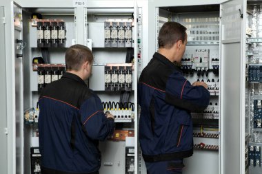 Elektrik mühendisi, elektrik kabinesi kontrolündeki voltaj ve elektrik akımını ölçen bir testçi ve röle koruma sistemindeki kabloları kontrol ediyor. Körfez kontrol birimi. Orta gerilim şalteri..