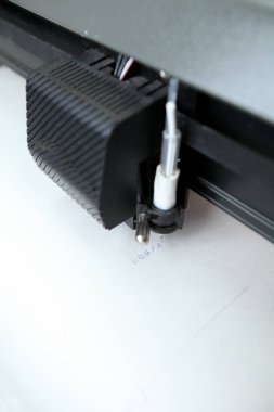 Computerized robot for automatic writing with a pen. Sewing shop. Material marking is automated. Robotic arm with black pen drawing.