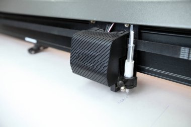 Computerized robot for automatic writing with a pen. Sewing shop. Material marking is automated. Robotic arm with black pen drawing.