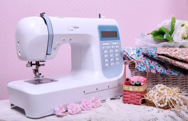 Composition from a sewing machine. Mannequin, flowers on a retro table and threads. Sewing supplies and composition with a sewing machine in the interior. With the letter M. The composition is unique for the fashion.