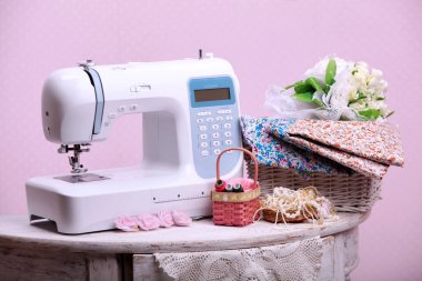 Composition from a sewing machine. Mannequin, flowers on a retro table and threads. Sewing supplies and composition with a sewing machine in the interior. With the letter M. The composition is unique for the fashion.