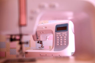 Composition from a sewing machine. Mannequin, flowers on a retro table and threads. Sewing supplies and composition with a sewing machine in the interior. With the letter M. The composition is unique for the fashion.