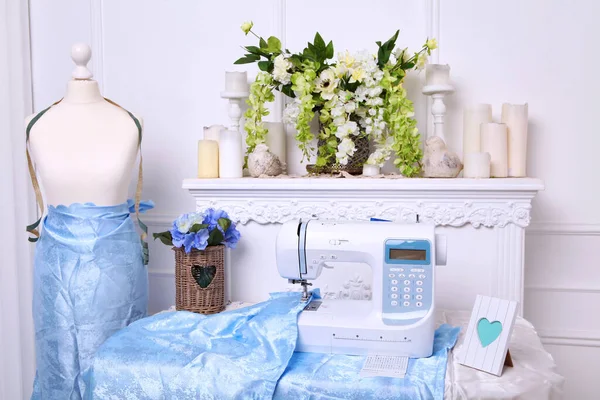 Composition from a sewing machine. Mannequin, flowers on a retro table and threads. Sewing supplies and composition with a sewing machine in the interior. With the letter M. The composition is unique for the fashion.