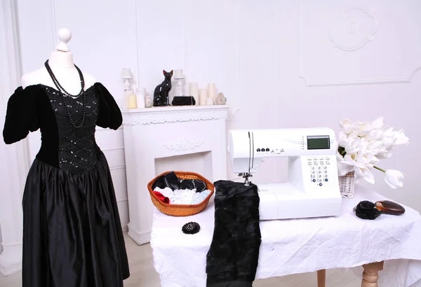 Composition from a sewing machine. Mannequin, flowers on a retro table and threads. Sewing supplies and composition with a sewing machine in the interior. With the letter M. The composition is unique for the fashion.