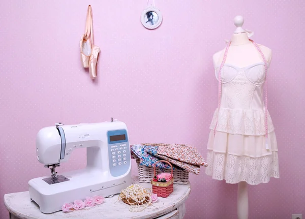 Composition from a sewing machine. Mannequin, flowers on a retro table and threads. Sewing supplies and composition with a sewing machine in the interior. With the letter M. The composition is unique for the fashion.