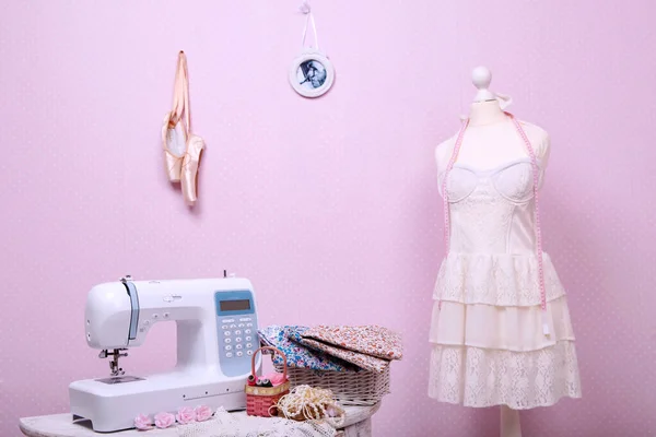 Composition from a sewing machine. Mannequin, flowers on a retro table and threads. Sewing supplies and composition with a sewing machine in the interior. With the letter M. The composition is unique for the fashion.