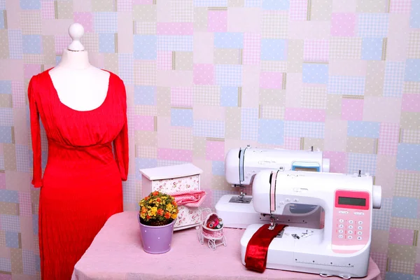 Composition from a sewing machine. Mannequin, flowers on a retro table and threads. Sewing supplies and composition with a sewing machine in the interior. With the letter M. The composition is unique for the fashion.