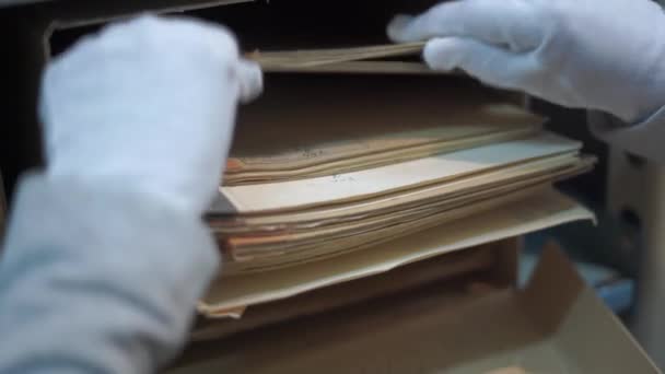Arbetstagaren letar efter journaler liggande i rutan på hyllan — Stockvideo