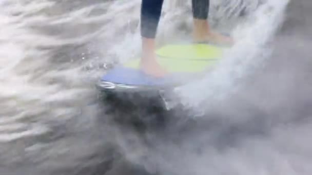 Hombre wakesurfs de pie en el tablero de colores entre las olas — Vídeos de Stock