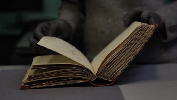 Бібліотекарі перевертають сторінки старої книги, лежачи на столі в бібліотеці — стокове відео