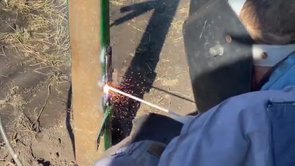 Mann in Schutzschild und Handschuhen schweißt Stahlkonstruktion zusammen — Stockvideo