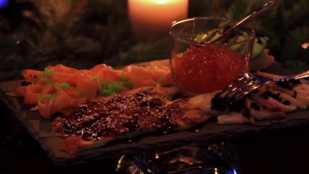 Placa con pescado en rodajas y caviar en tazón a la luz de las velas — Vídeos de Stock