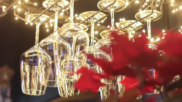Glasses hang on stand with upper illumination in restaurant — Stockvideo