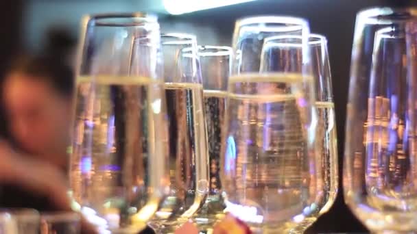 Set of crystal wineglasses hangs on stand with upper illumination in restaurant. — Stock video