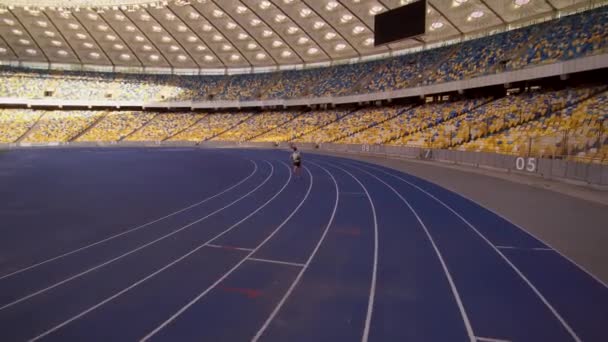 穿着运动服的运动员在一个空荡荡的大体育场周围的长跑跑道上跑着 职业赛跑选手训练得很辛苦 准备参加奥运会比赛 乌克兰 基辅2022年7月 — 图库视频影像