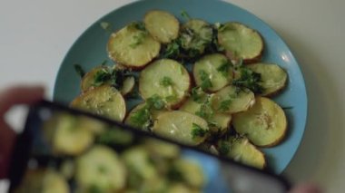 Kadın, patates dilimli maydanozun fotoğrafını çekiyor.