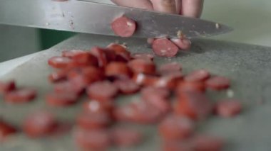 Ev hanımı sosisleri bıçakla küçük dilimlere ayırır.