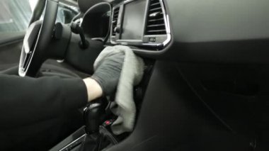 Adam sürücü koltuğunda oturan deterjanla araba yıkama salonunu temizliyor.