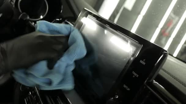 Чоловік в рукавичках очищає чорний автомобіль від пилу з миючим засобом, що сидить на водійському сидінні. Чорний автомобільний салон — стокове відео