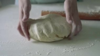 Kadın un masaya çiğ hamur fırlatıyor.