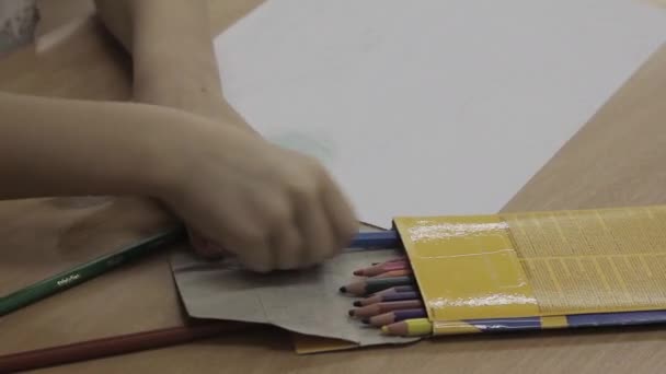 幼儿园的小提琴手把彩色铅笔放在木制桌旁空白纸片旁边的盒子里 幼稚园特写课上儿童绘画课 — 图库视频影像