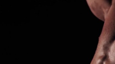 Genç güçlü adam spor salonunda kaslarını şişiriyor. Yakın plan.