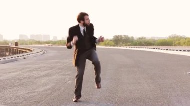 Genç adam zaferle seviniyor, mutlulukla zıplıyor ve dans ediyor.