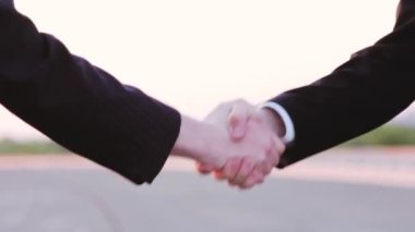 Genç adamlar şafakta el sıkışıyor. Sokakta.