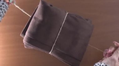 Kadın kumaş parçasını iple bağlar ve yay yapar.