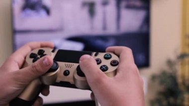 Çocuğun elleri büyük TV ekranı karşısında konsoldaki düğmelere basıyor