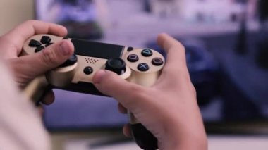 Çocuğun elleri TV 'nin büyük ekranına karşı oyun konsolunun düğmelerine basar