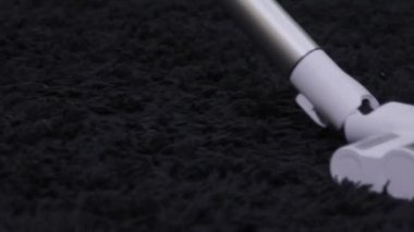 Elektrikli süpürge odadaki siyah halıyı temizliyor. Bir elektrik süpürgesinin yakın çekimi