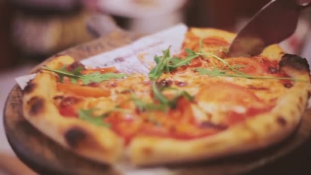 女性ウエイターはレストランのゲストにホットピザを提供しています ボード上のスライスピザ — ストック動画