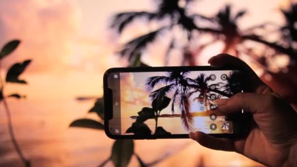 Woman Filming Sunset Beach Her Phone Waves Palm Trees Sand – stockvideo