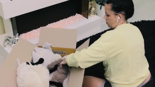 Woman Takes Out Soft Toys Cardboard Box While Sitting Floor — Stockvideo