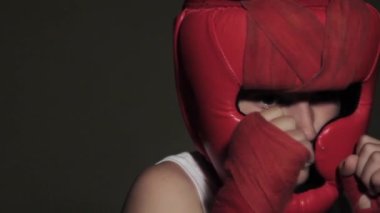 Young guy boxer in a protective stance looks at the camera. Red helmet on head