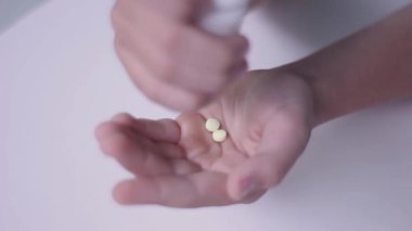 Adam baş ağrısını azaltmak için avucunun içine beyaz haplar döküyor.
