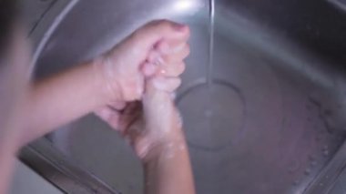 Mutfaktaki suyun basıncıyla sabunu ellerinden yıka. Çocuklar elleri çerçevede yakın çekimde.