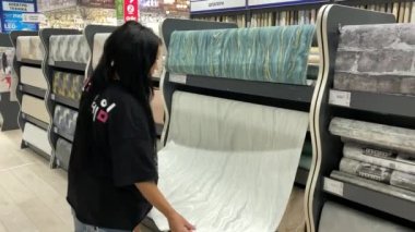 Duvar kâğıdı bölümündeki bir süpermarkette duvarlar için bir ev ve apartman dairesinde çalışan genç bir kız.