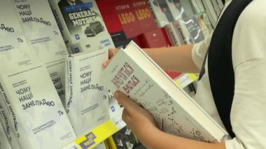 Young man guy buys books in the supermarket for school and study. Ukraine, Kyiv July 2022