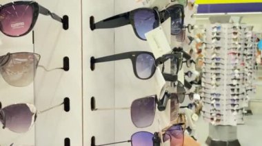 Guy chooses sunglasses in the store. Revolving glasses stand for shopping. Ukraine, Kyiv July 2022