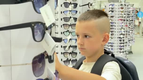 Young Guy Chooses Sunglasses Spinning Stand Supermarket Sunglasses Shelf Ukraine — Vídeo de Stock