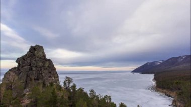 Rock against the background of the sky and Lake Baikal in sunny weather. The movement of clouds and a picturesque landscape on the tops of mountains