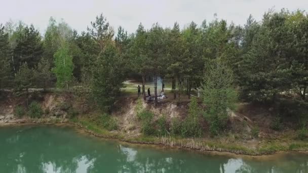 Een groep vrienden hebben een goede tijd in een dennenbos in de buurt van het blauwe meer in de zomer, vanuit de lucht. Natuur van Oekraïne, prachtig landschap. — Stockvideo
