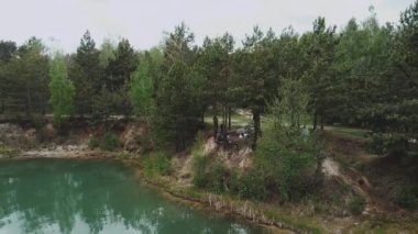 Bir grup arkadaşın hava manzarası açık mavi göl yakınlarındaki bir çam ormanında kamp ateşi yakınında iyi vakit geçiriyor. Ukrayna doğası, güzel manzara..