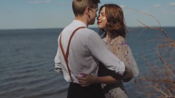 Killen kommer fram till flickan, kramar och smeker hennes hår, flickan ler mot honom. Närbild av par i kärlek kramar, är havet i bakgrunden. — Stockvideo