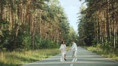 Neşeli genç Avrupalı bir çift, çam ormanında yumuşak doğal ışıklandırmayla pitoresk bir yerde yürüyor. Çift öpüşüyor, sarılıyor, el ele tutuşuyor, öpüşüyor ve sarılıyor. . 