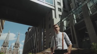 Man looking to camera while standing outdoors business building on the background. Medium shot Portrait of male person dressed in stylish clothes .
